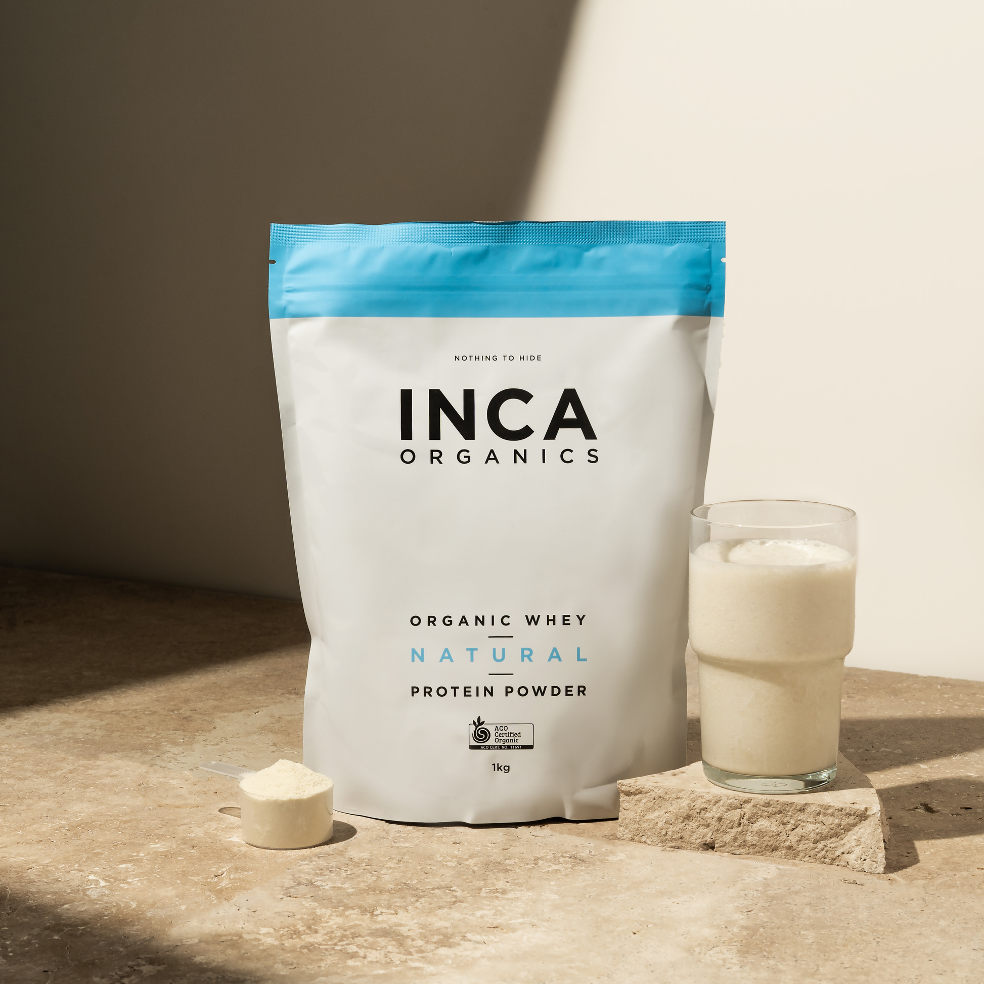 INCA Organics protein powder bag with a glass of milk on a wooden surface